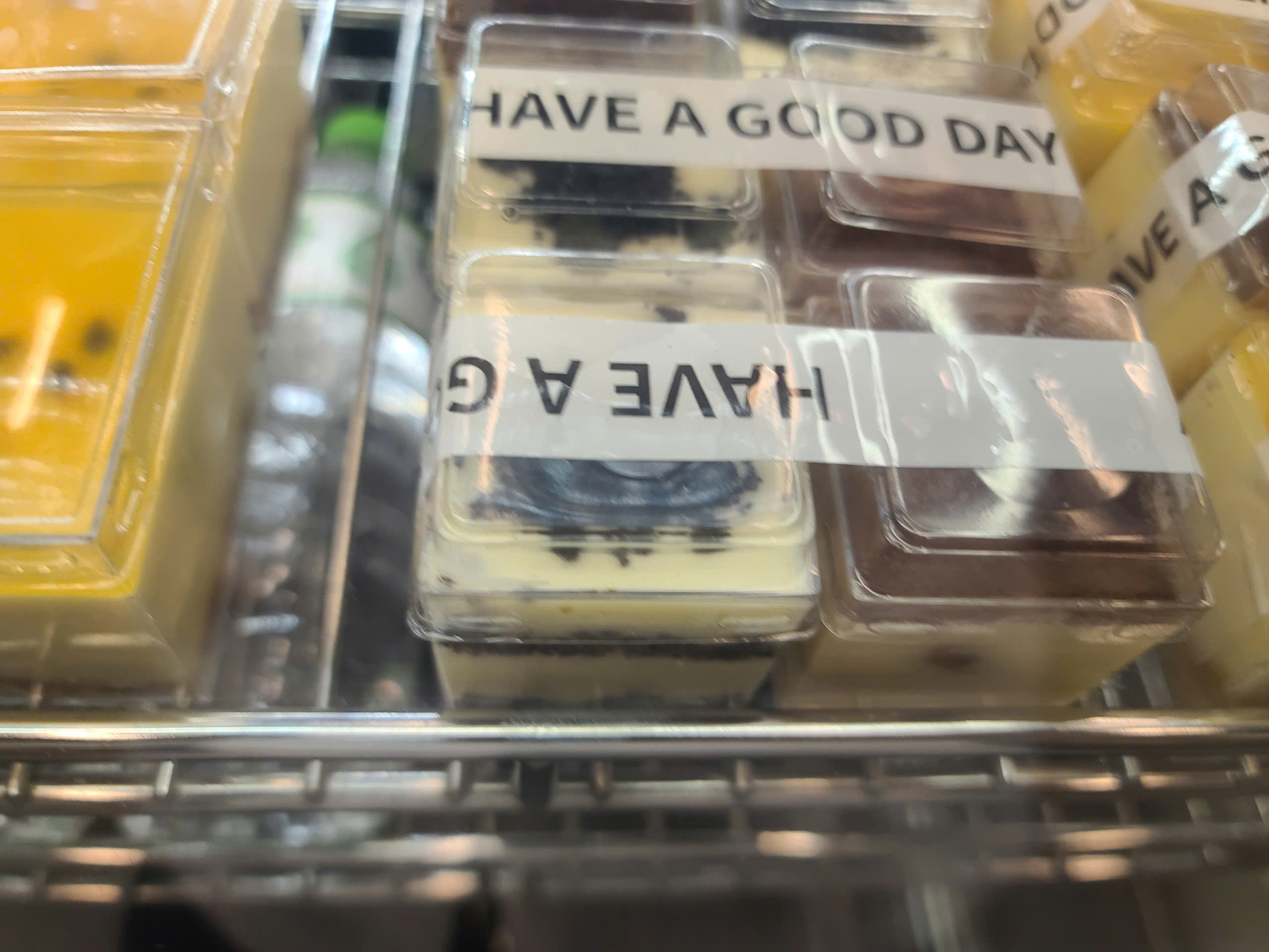 Small containers with wax melts labeled 'Have a Good Day' on a metal rack.